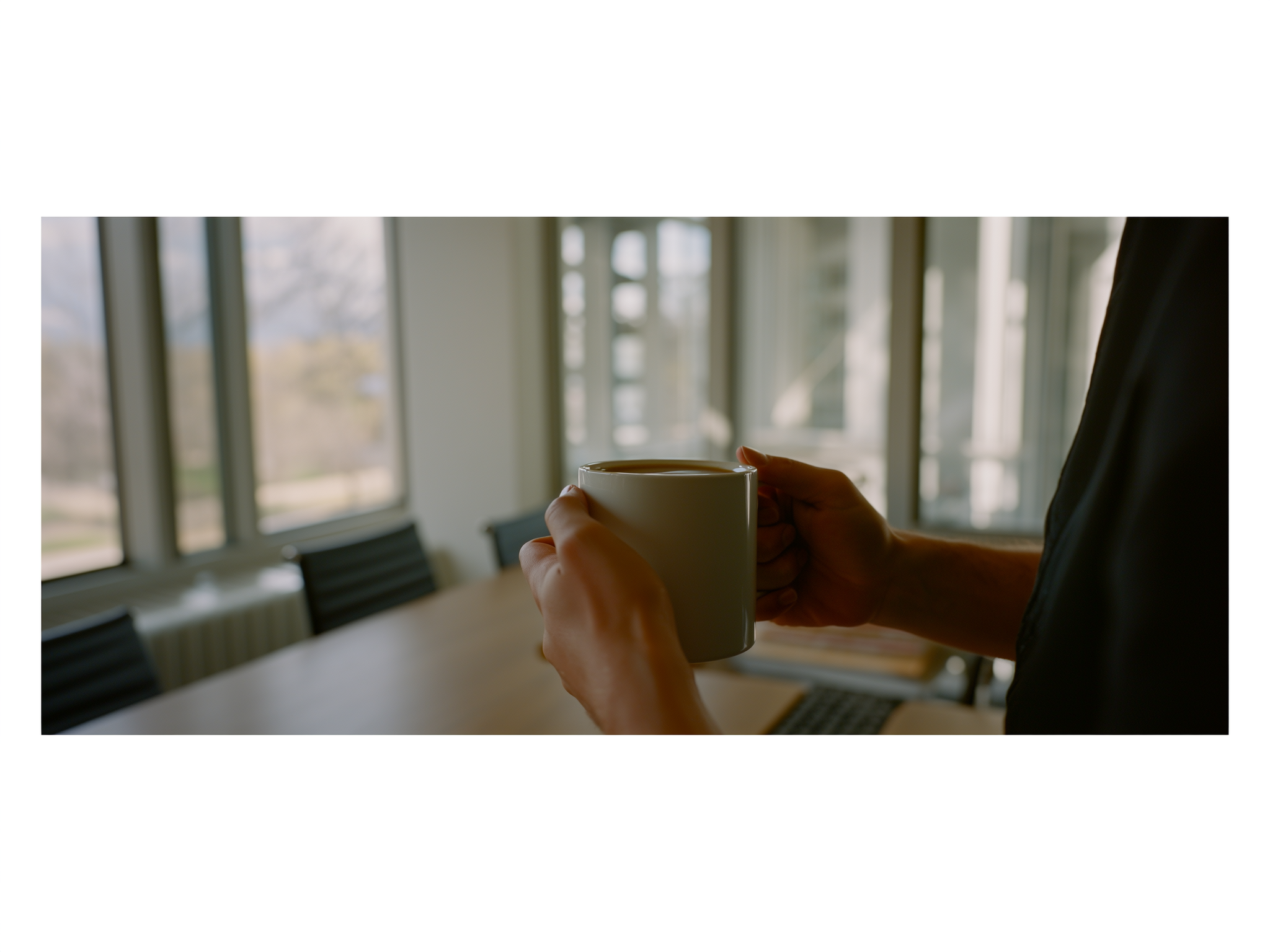 Manos sosteniendo una taza de café en ambiente de oficina relajado