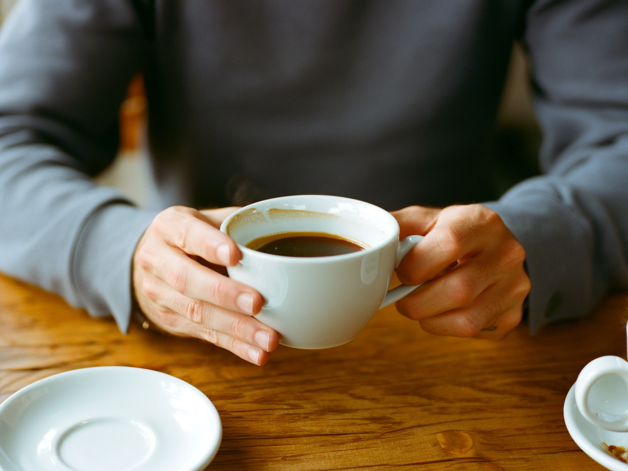 Manos sosteniendo una taza de café en un ambiente acogedor, representando momentos de calma en el presente