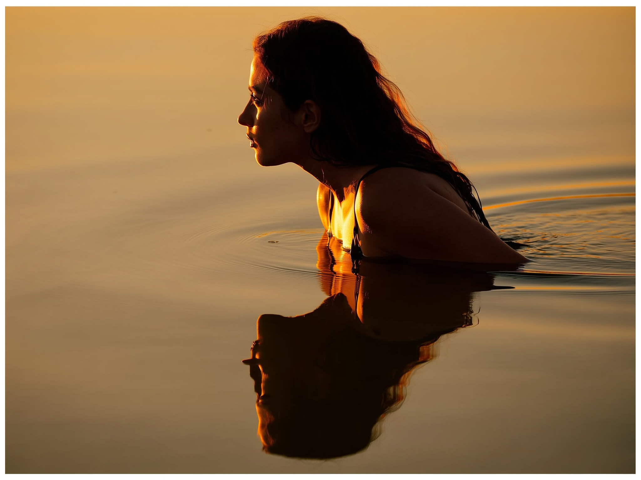 Reflejo sereno de una mujer en las aguas tranquilas de un lago al atardecer