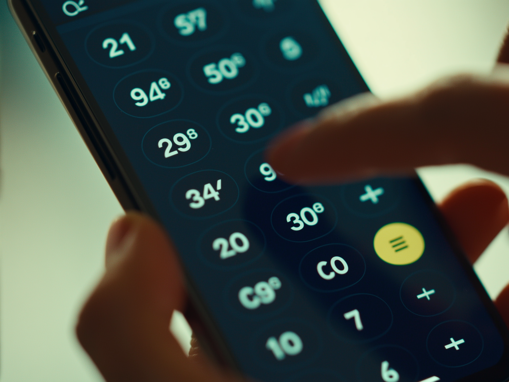 Manos usando calculadora en smartphone con luz natural