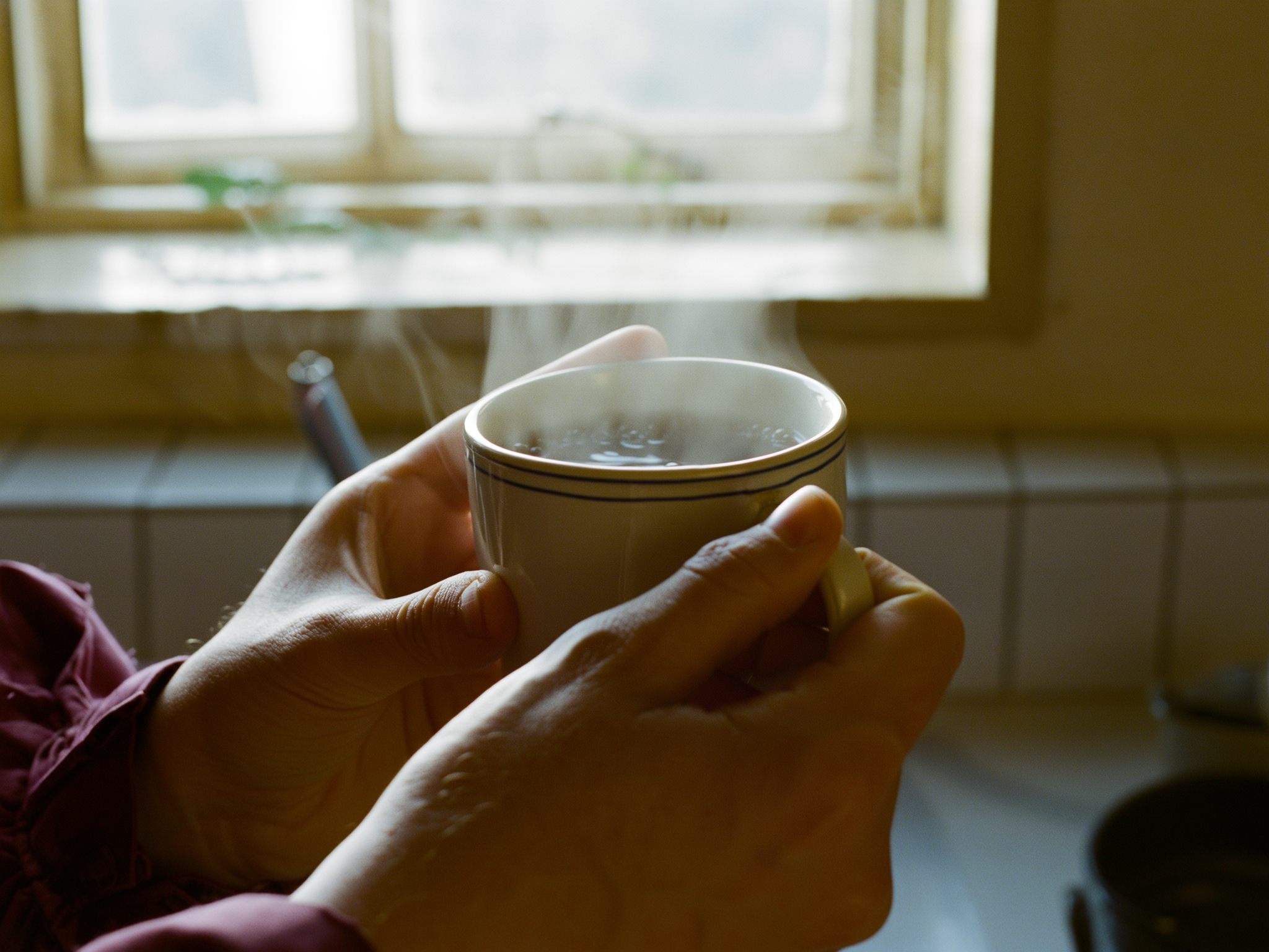 Manos sosteniendo una taza de té, reflejando momentos de ansiedad en casa