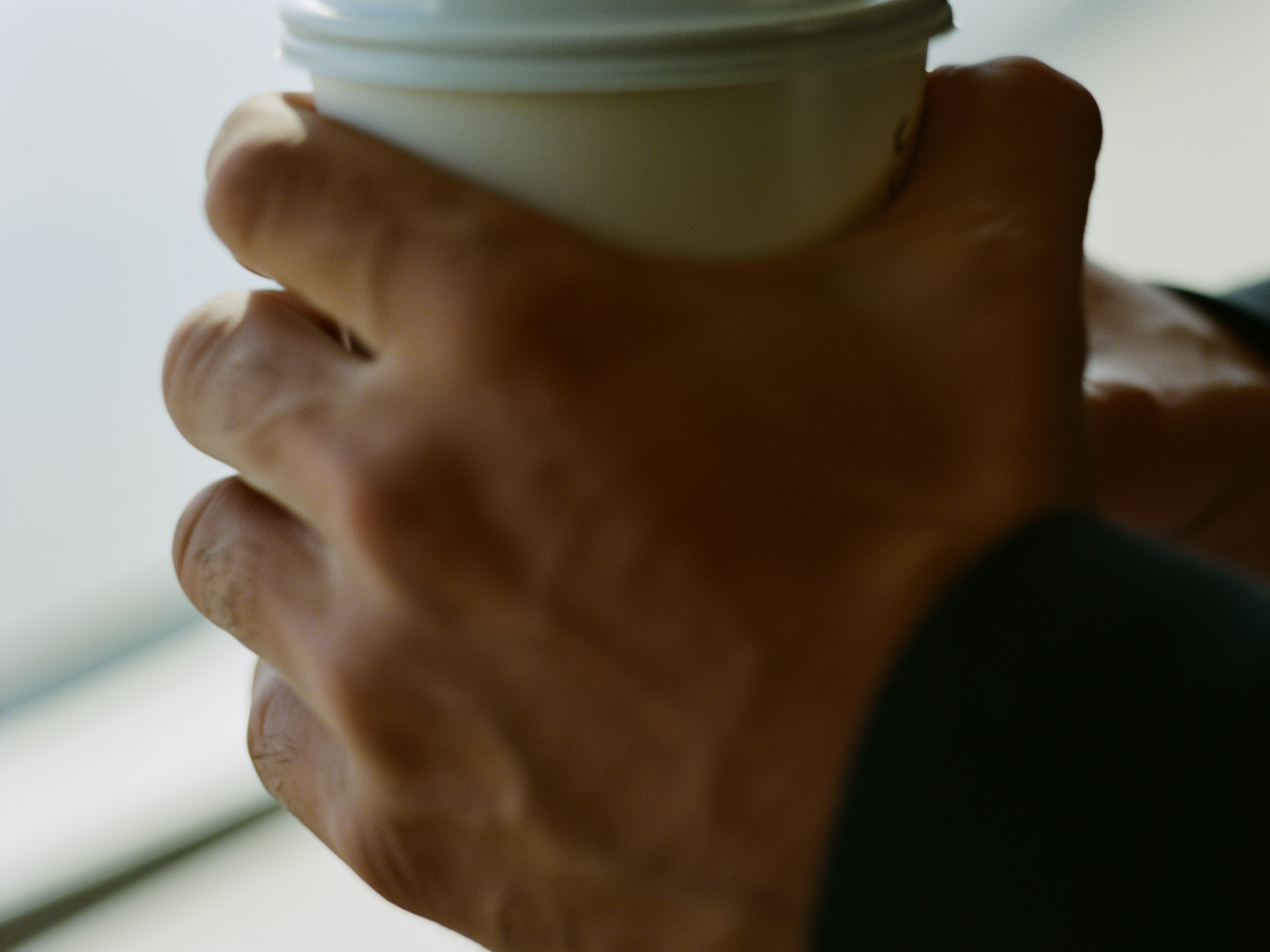 Manos sosteniendo una taza de café con tensión, simbolizando la ansiedad laboral