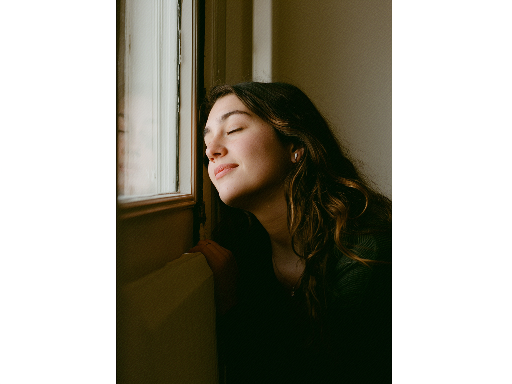 Mujer mirando serenamente por la ventana en una mañana invernal con luz natural suave