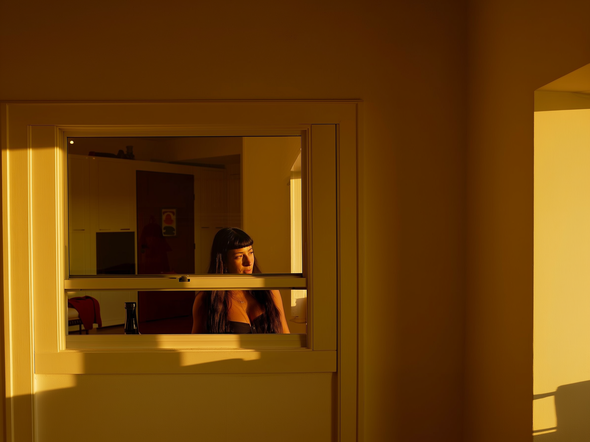 Mujer reflexionando junto a una ventana con luz cálida, representando la introspección antes de conocer a la familia política