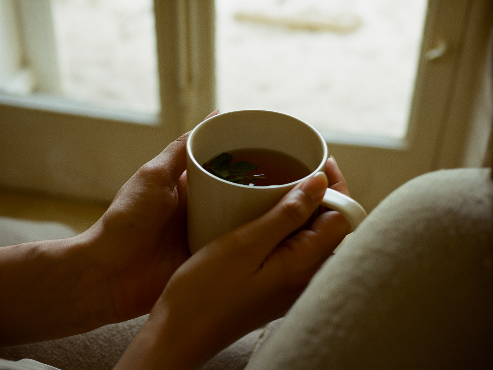Manos sosteniendo una taza de té en ambiente relajado y terapéutico
