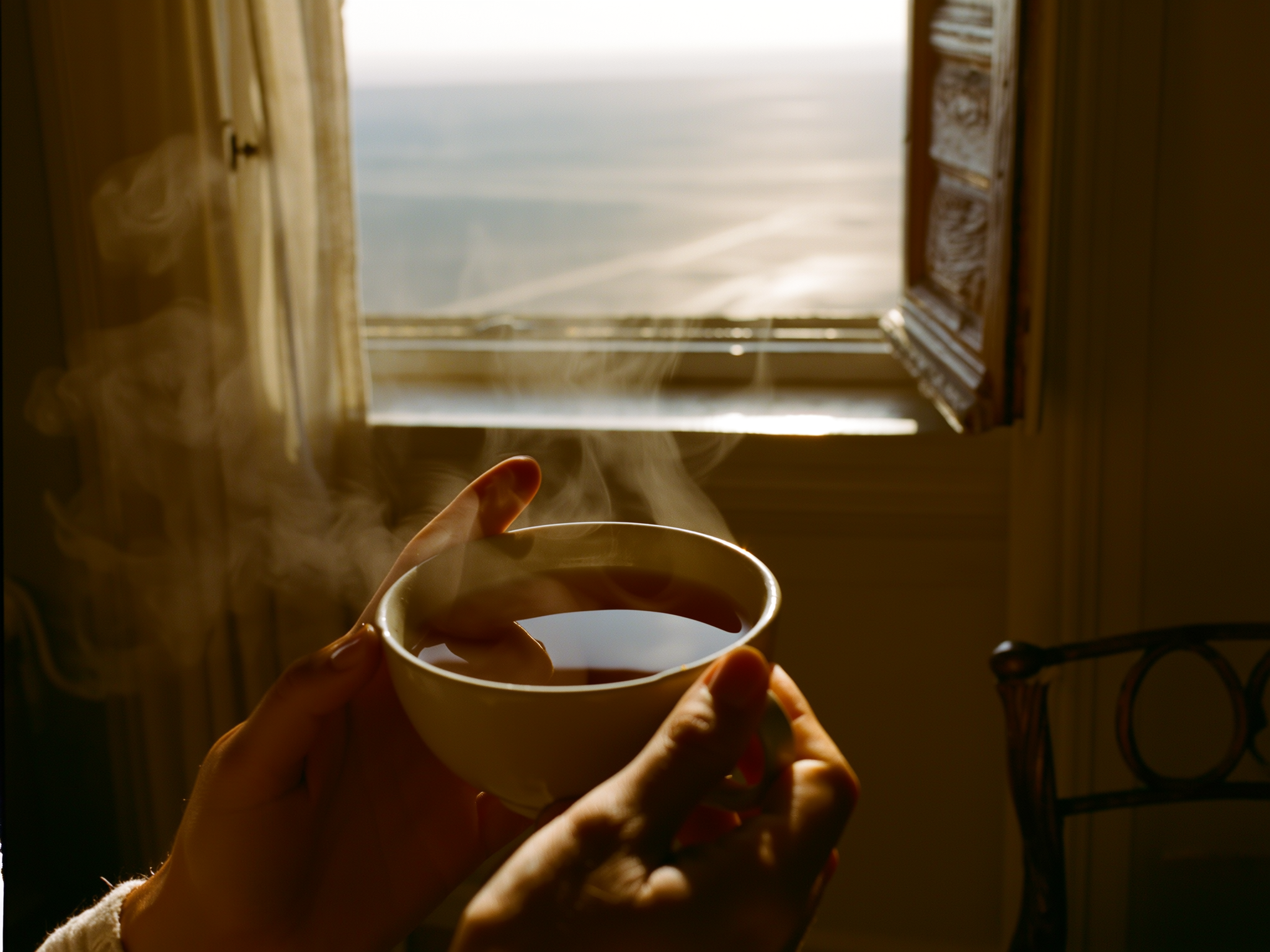 Manos sosteniendo una taza humeante en un ambiente hogareño y tranquilo