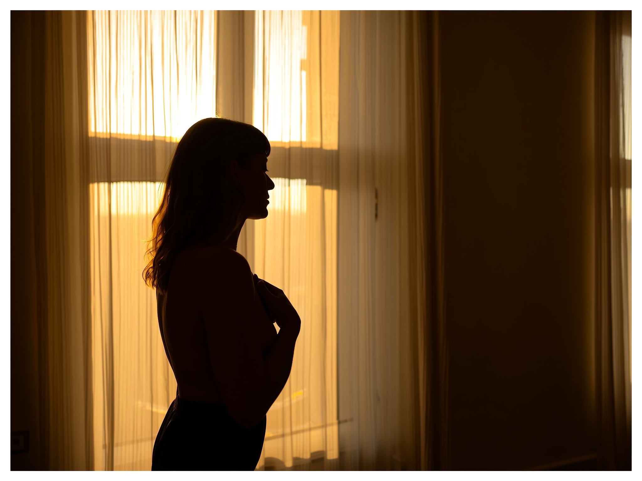 Mujer respirando profundamente junto a una ventana con luz natural suave
