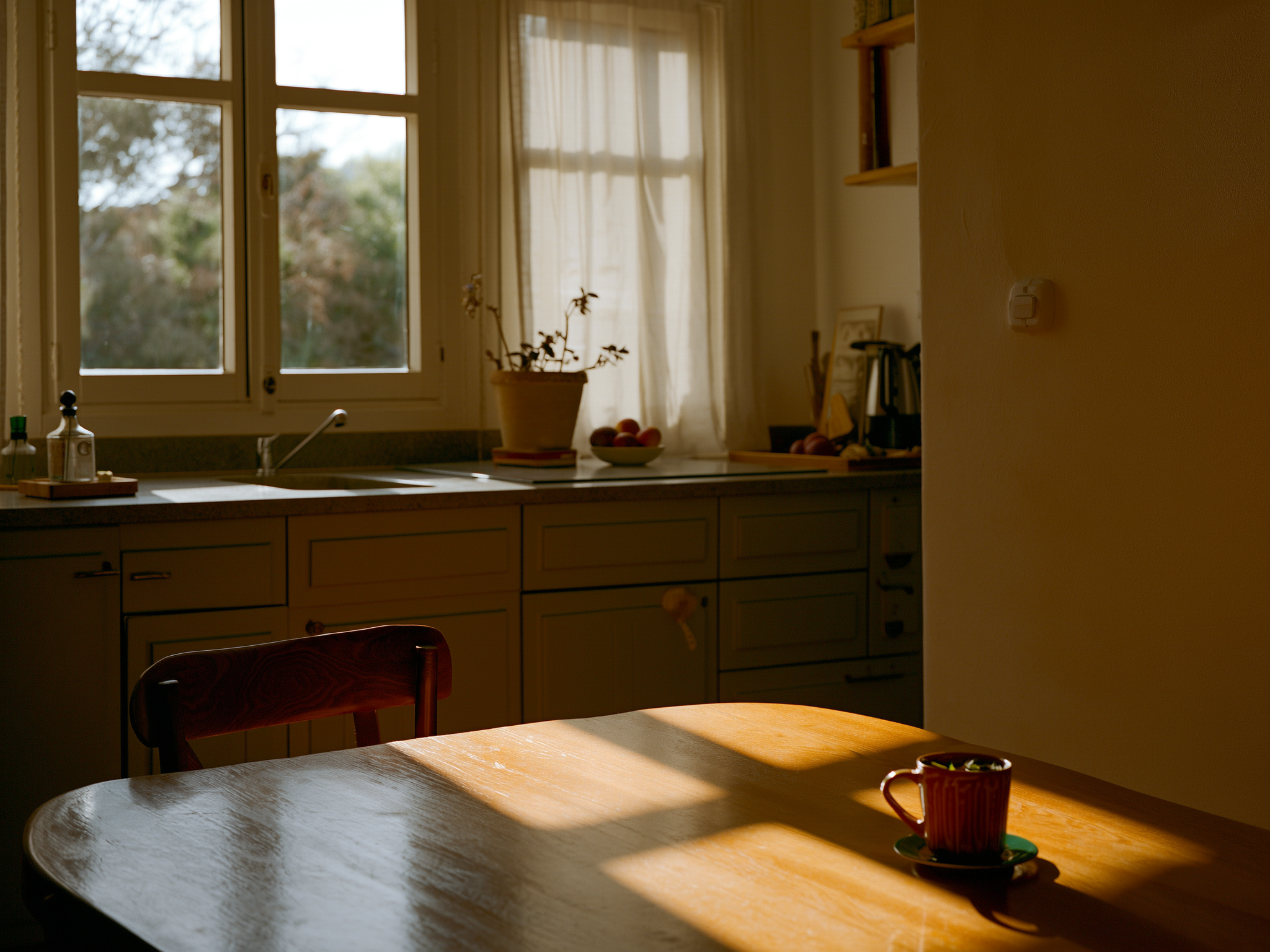 Mujer sentada en cocina con taza de té mirando por la ventana en momento de calma