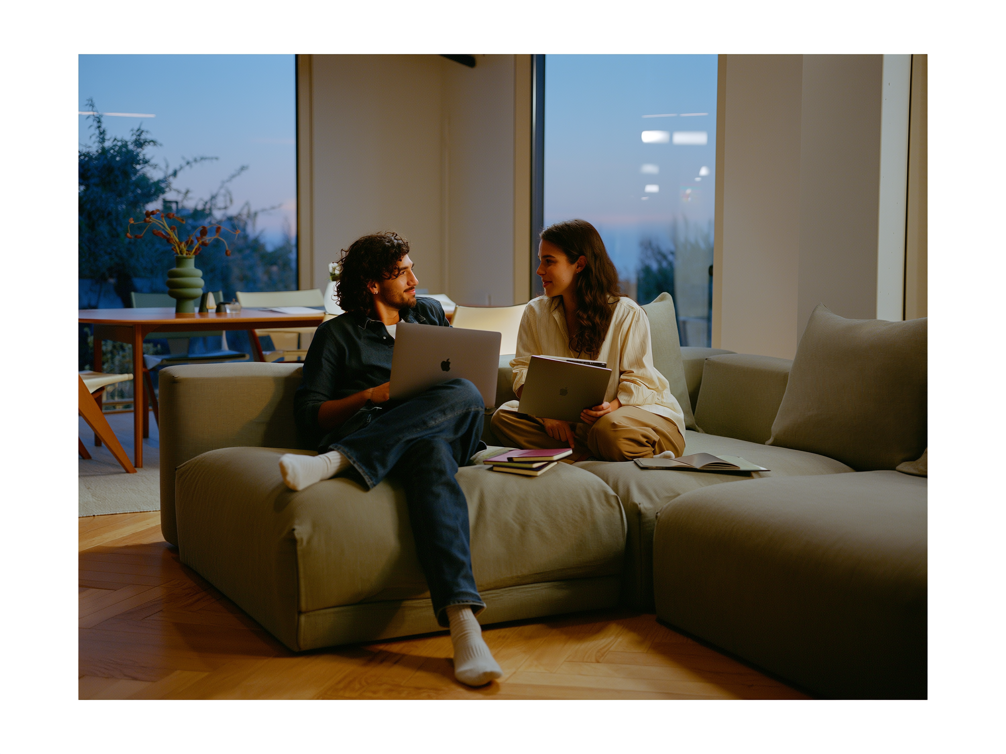 Pareja joven conversando tranquilamente sobre finanzas en el sofá de casa