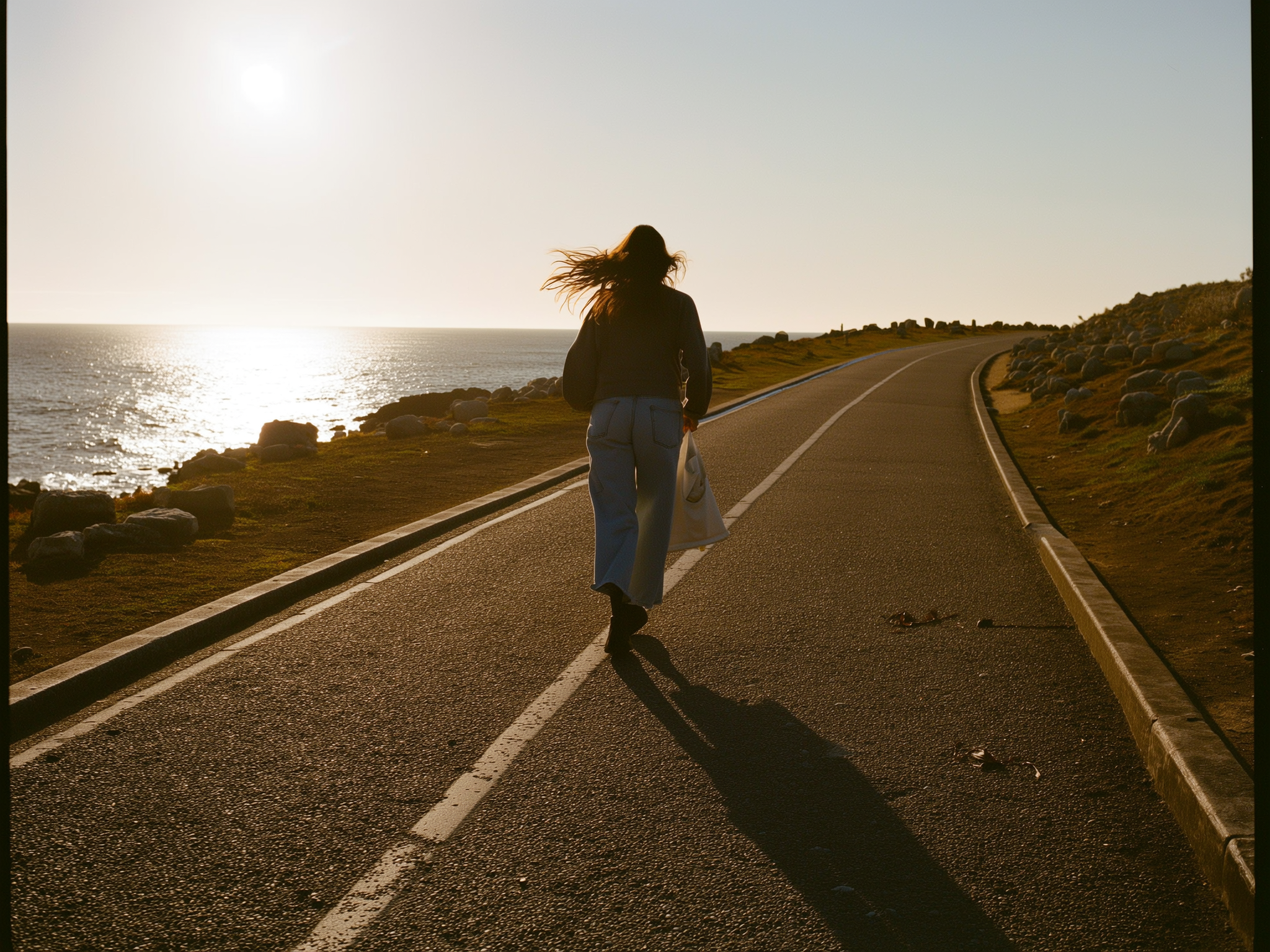 Mujer caminando por sendero costero al atardecer, simbolizando esperanza y nuevo comienzo