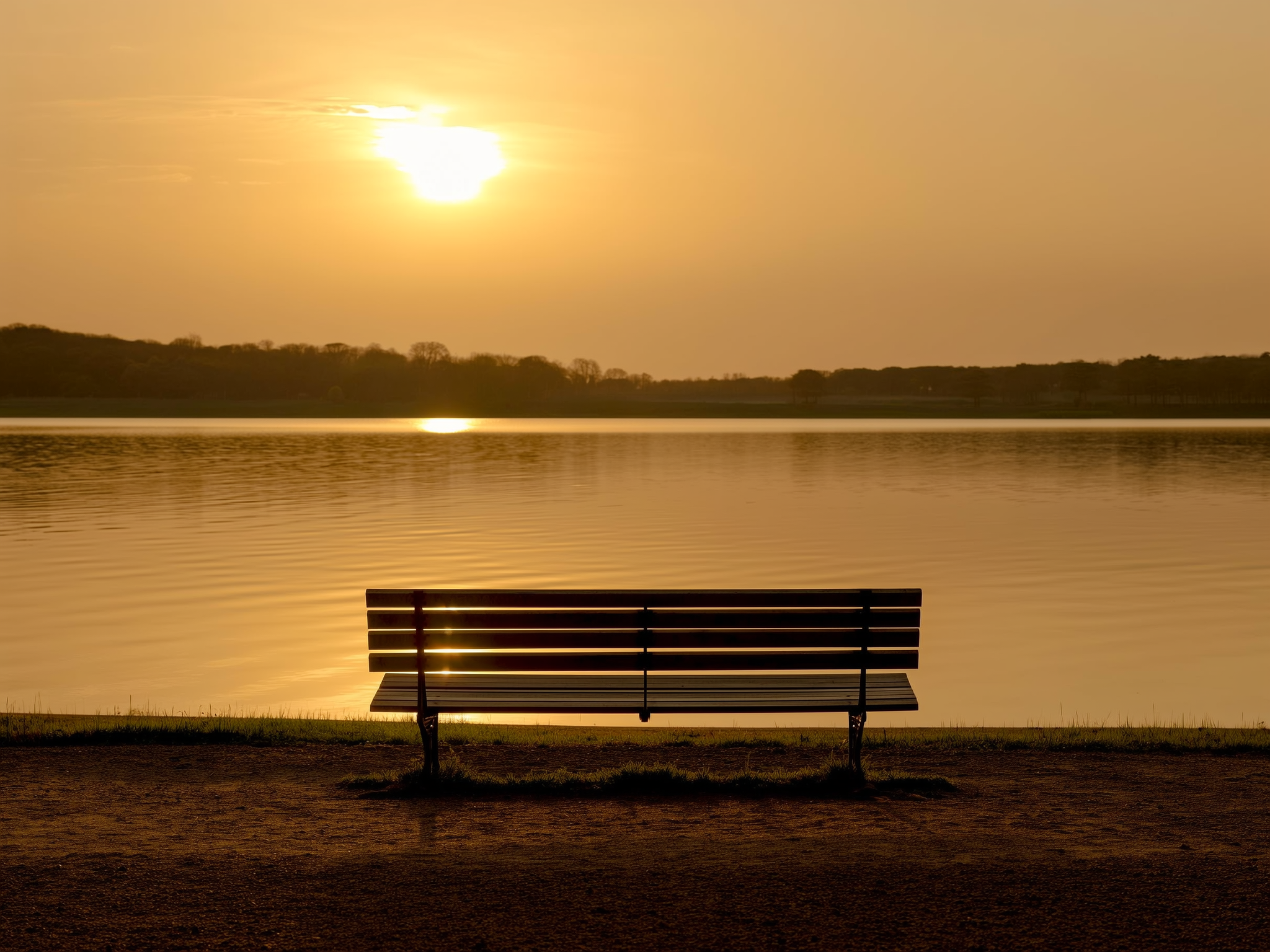 Banco vacío frente a un lago al atardecer simbolizando la reflexión vital