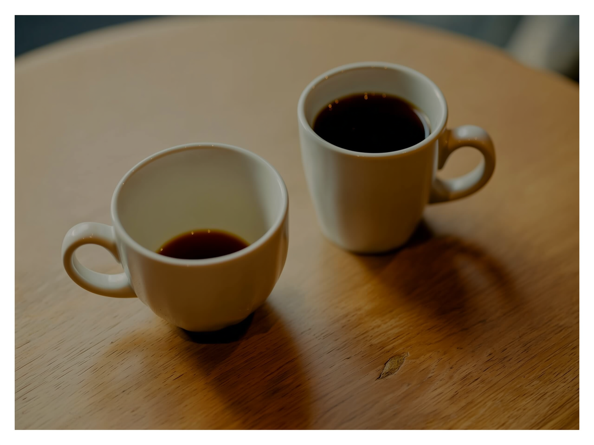 Dos tazas de café en mesa de madera simbolizando diferentes momentos en una relación