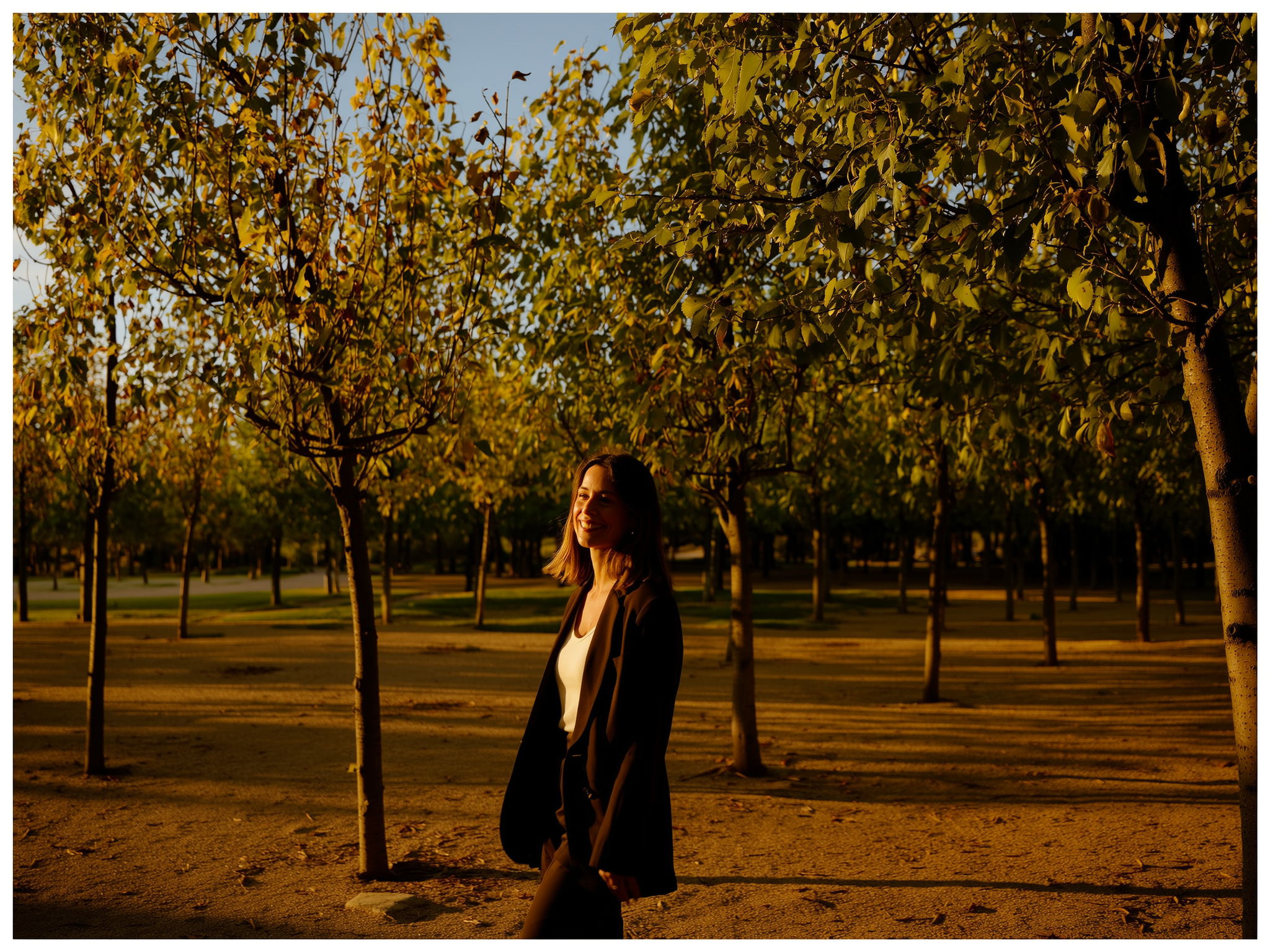 Mujer caminando tranquila por un parque durante el atardecer