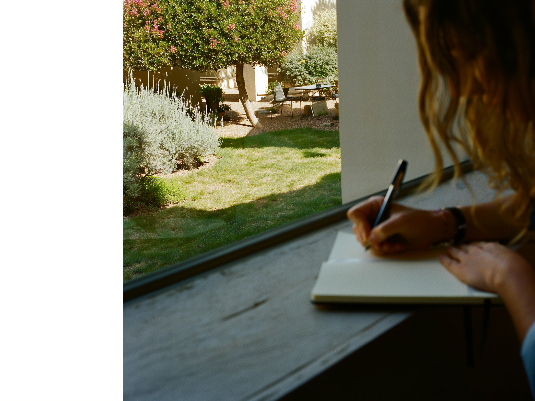 Persona escribiendo reflexiones en un cuaderno junto a una ventana