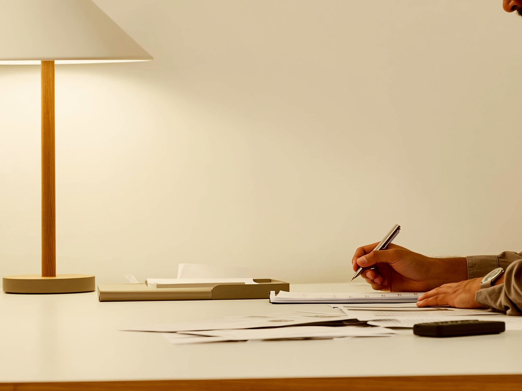 Manos escribiendo notas estratégicas en escritorio minimalista con luz natural