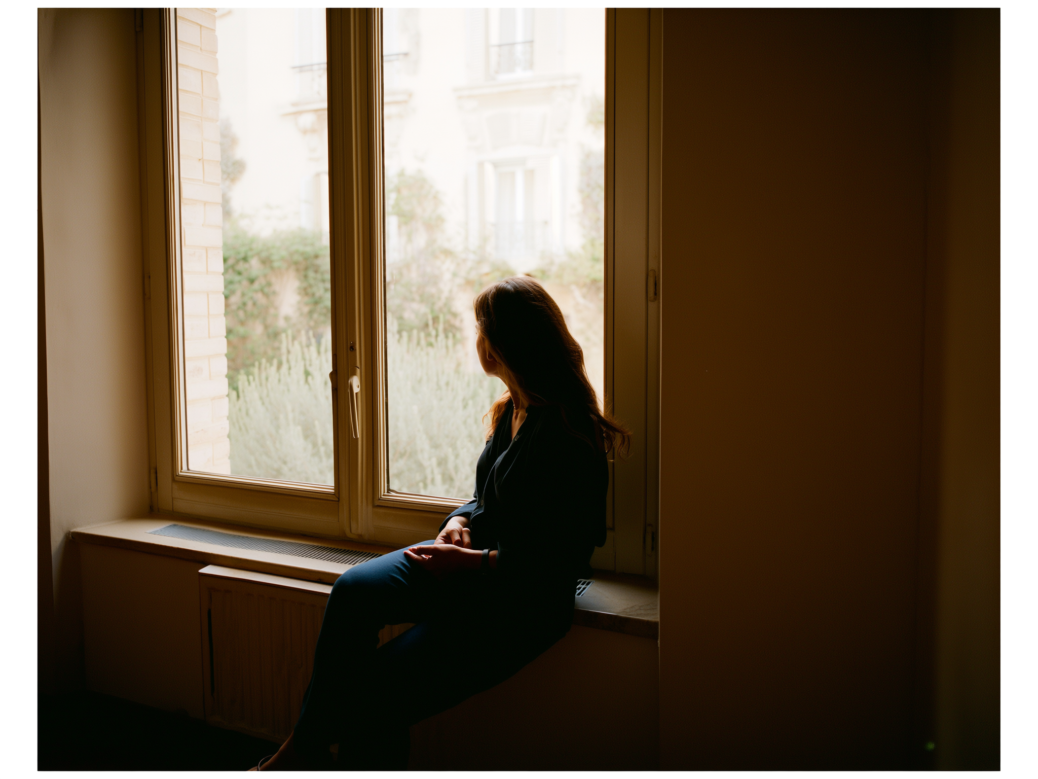 Mujer reflexionando junto a una ventana con luz suave, representando la introspección emocional
