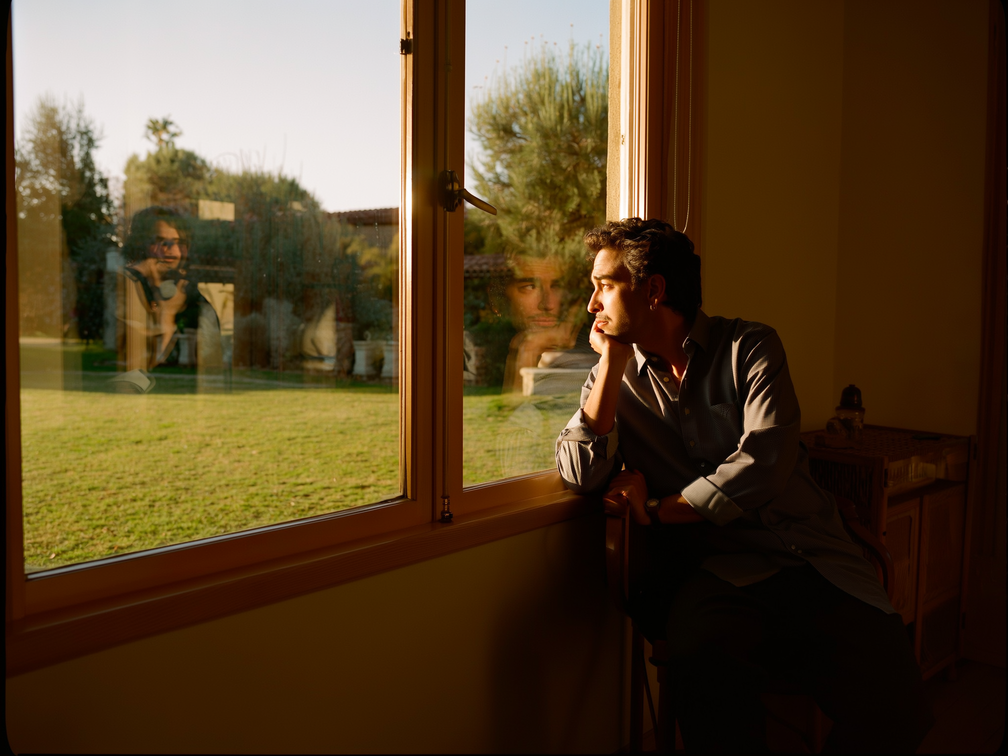 Persona adulta contemplando desde una ventana con luz suave, simbolizando reflexión y búsqueda de autonomía