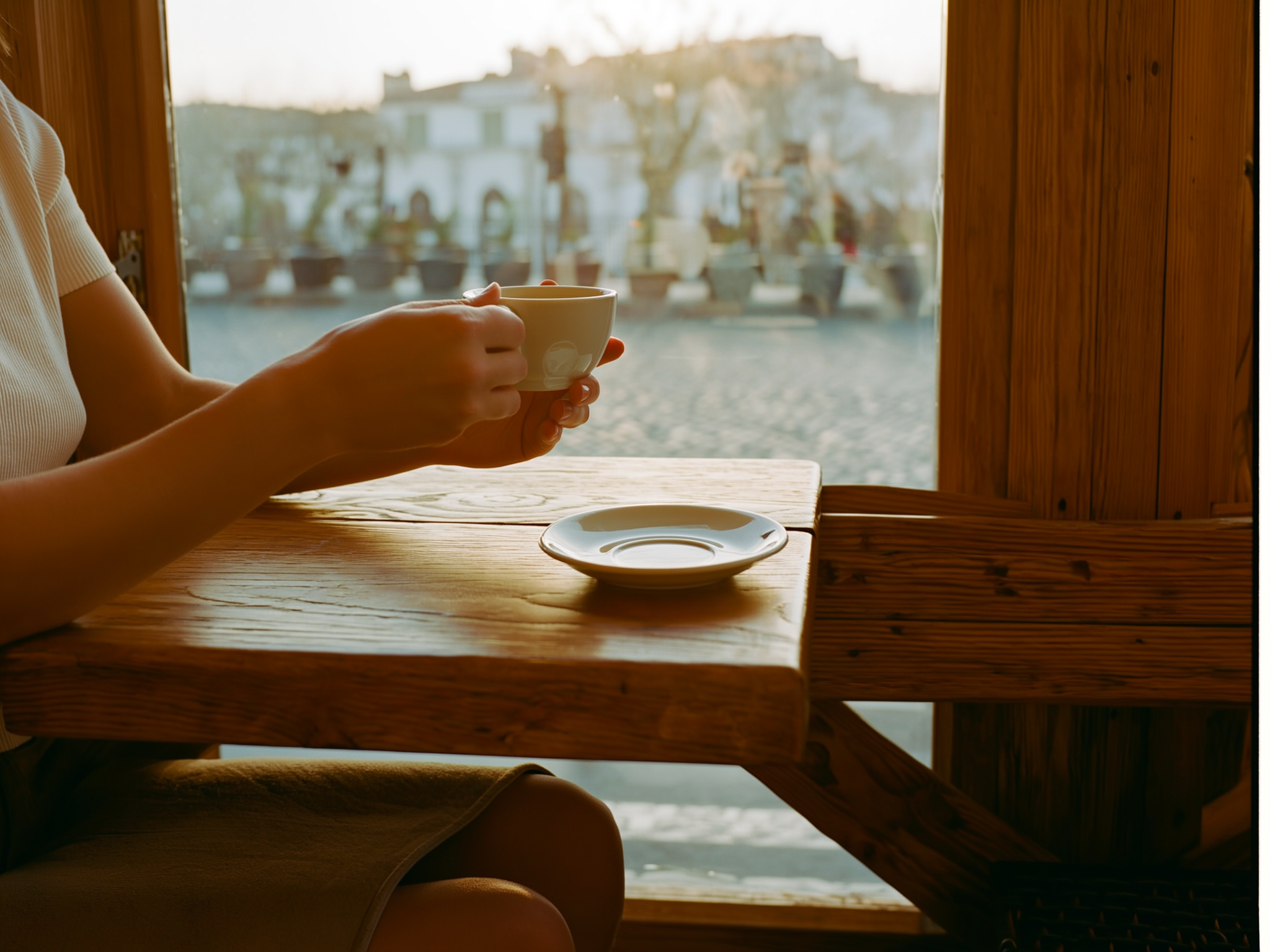 Manos sosteniendo una taza de té junto a una ventana con luz suave, representando momentos de calma y reflexión