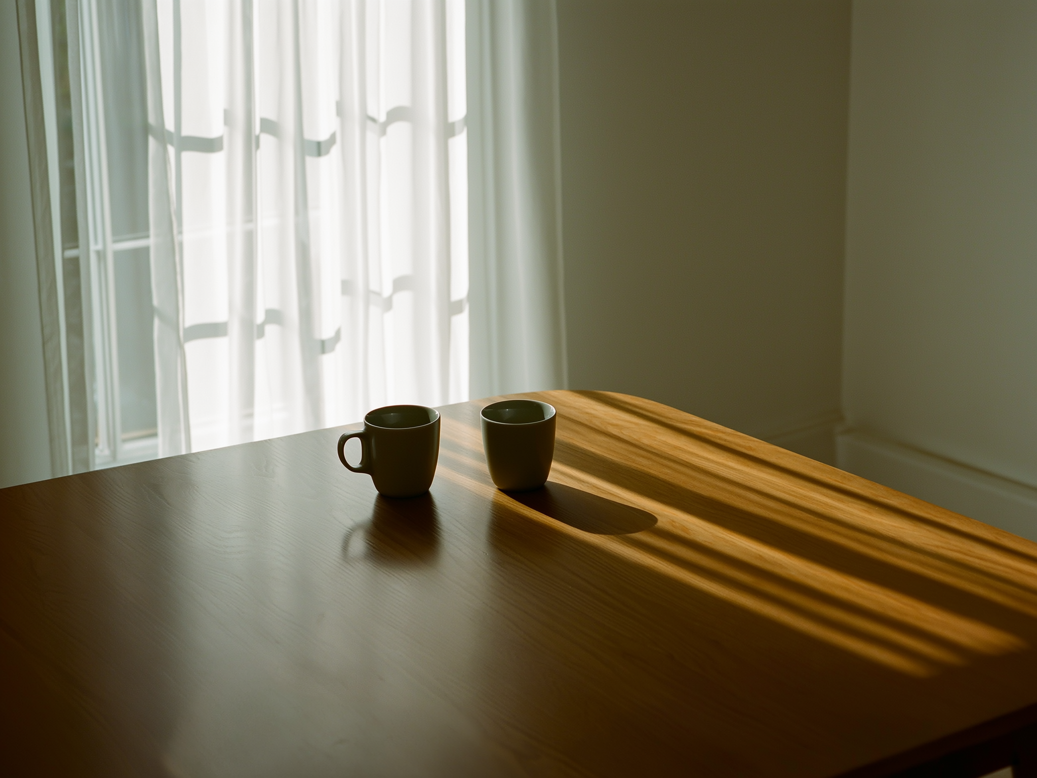 Mesa con tazas vacías en luz matutina suave, representando momentos de soledad contemplativa