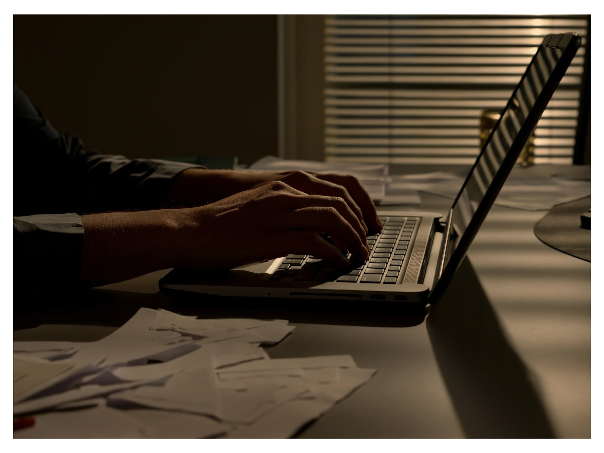 Manos trabajando en un escritorio con documentos, representando el agotamiento laboral