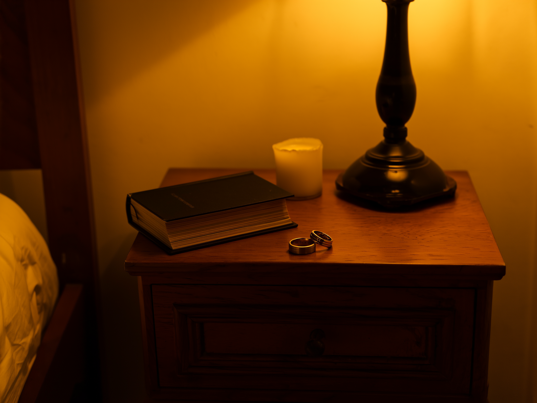 Anillos de matrimonio sobre mesita de noche con luz de velas