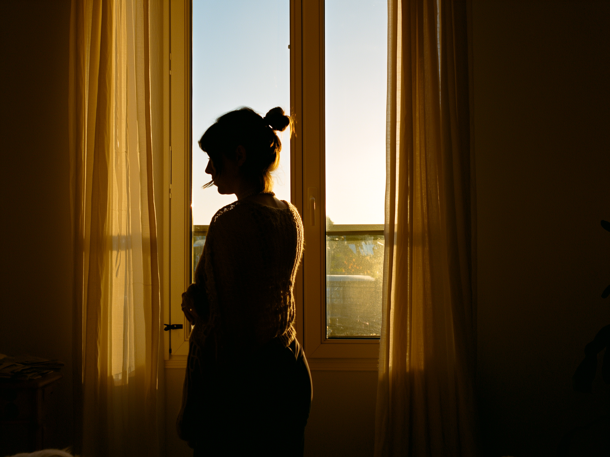Mujer reflexiva mirando por la ventana en momento de autoconocimiento y sanación emocional
