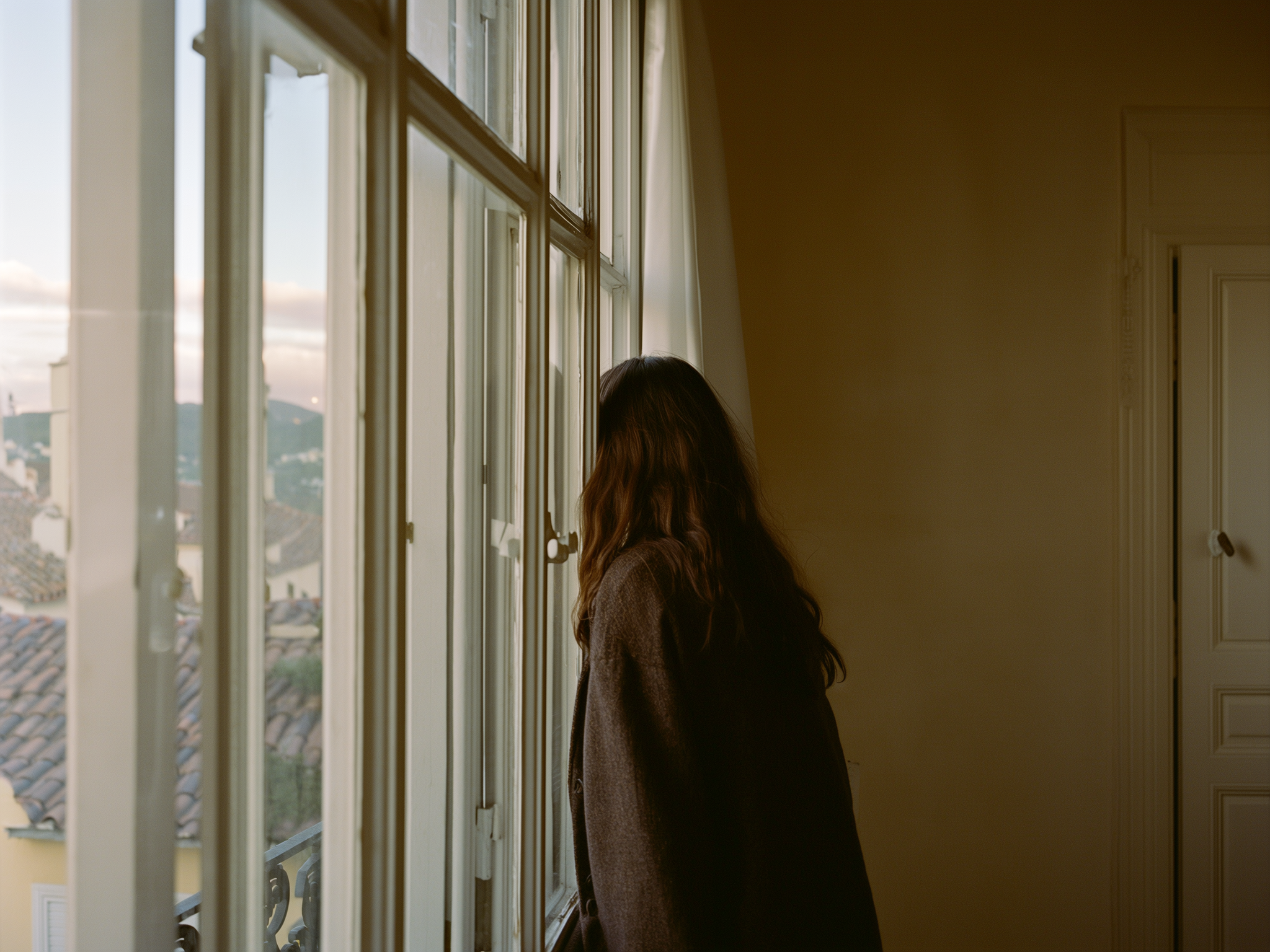 Persona contemplando desde una ventana, reflejando soledad emocional